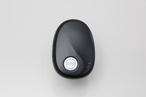 The FamilyCareConductor GPS tracker: a small black pendant-style device with a raised silver SOS button, viewed from above on a plain background.